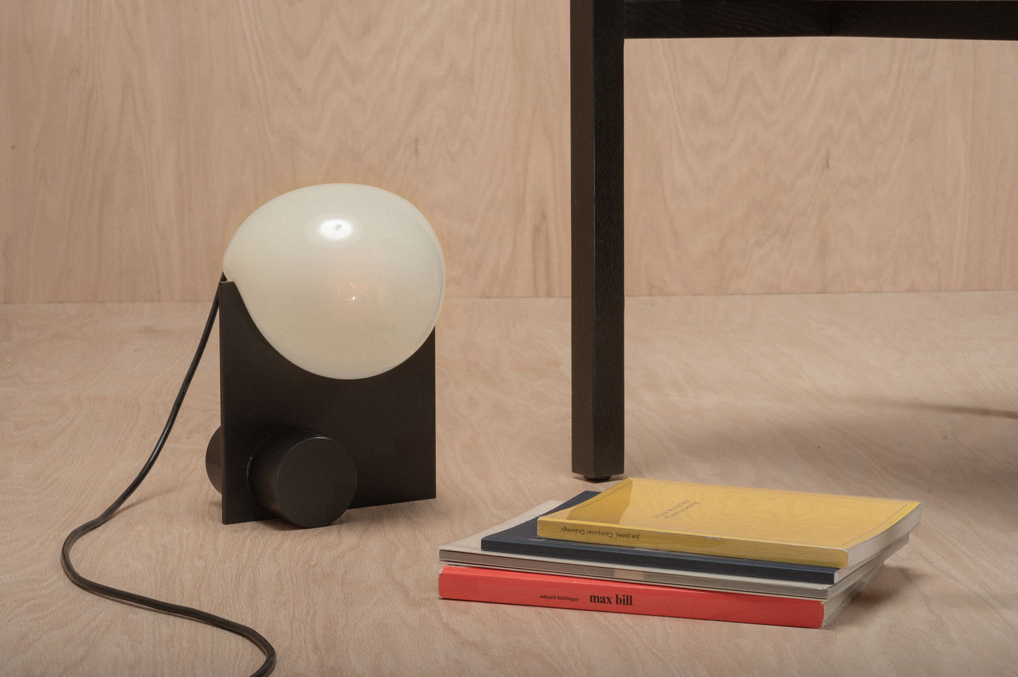 Bloop Table Lamp on the floor aside a stack of books
