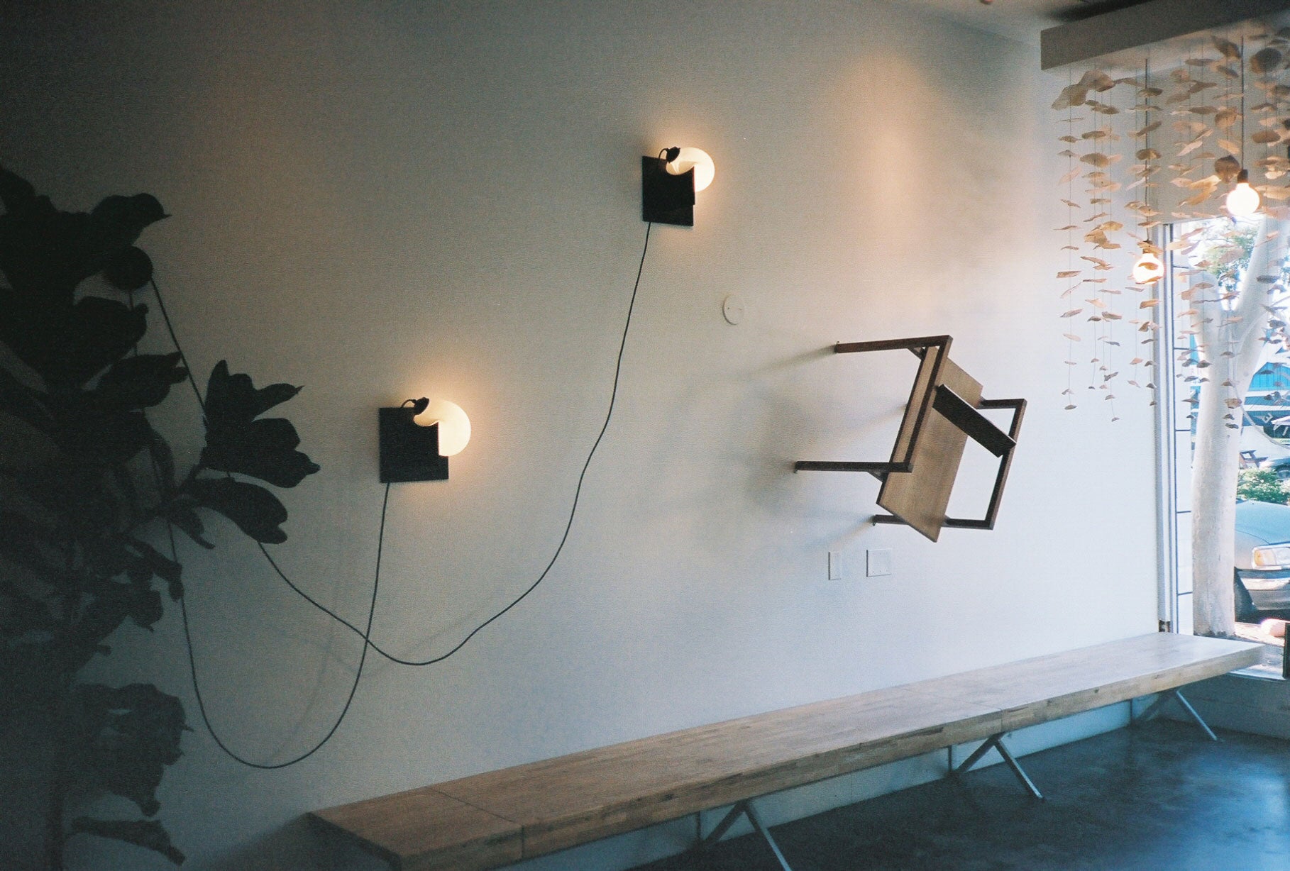 Box Chair mounted sideways on the wall of a cafe next to two Bloop Sconces