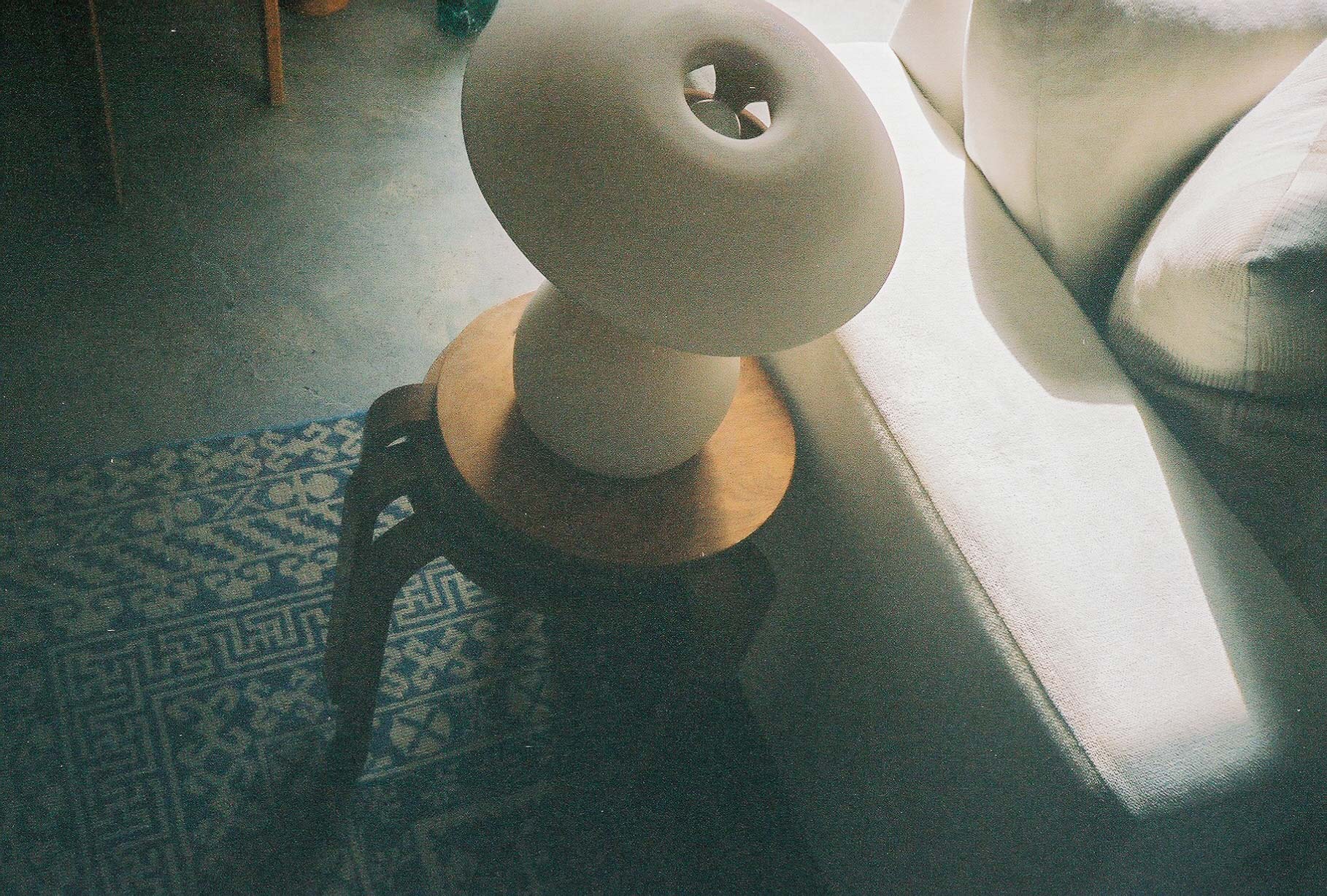 White Mushroom Lamp sitting atop a stack of Artek stools next to a white couch