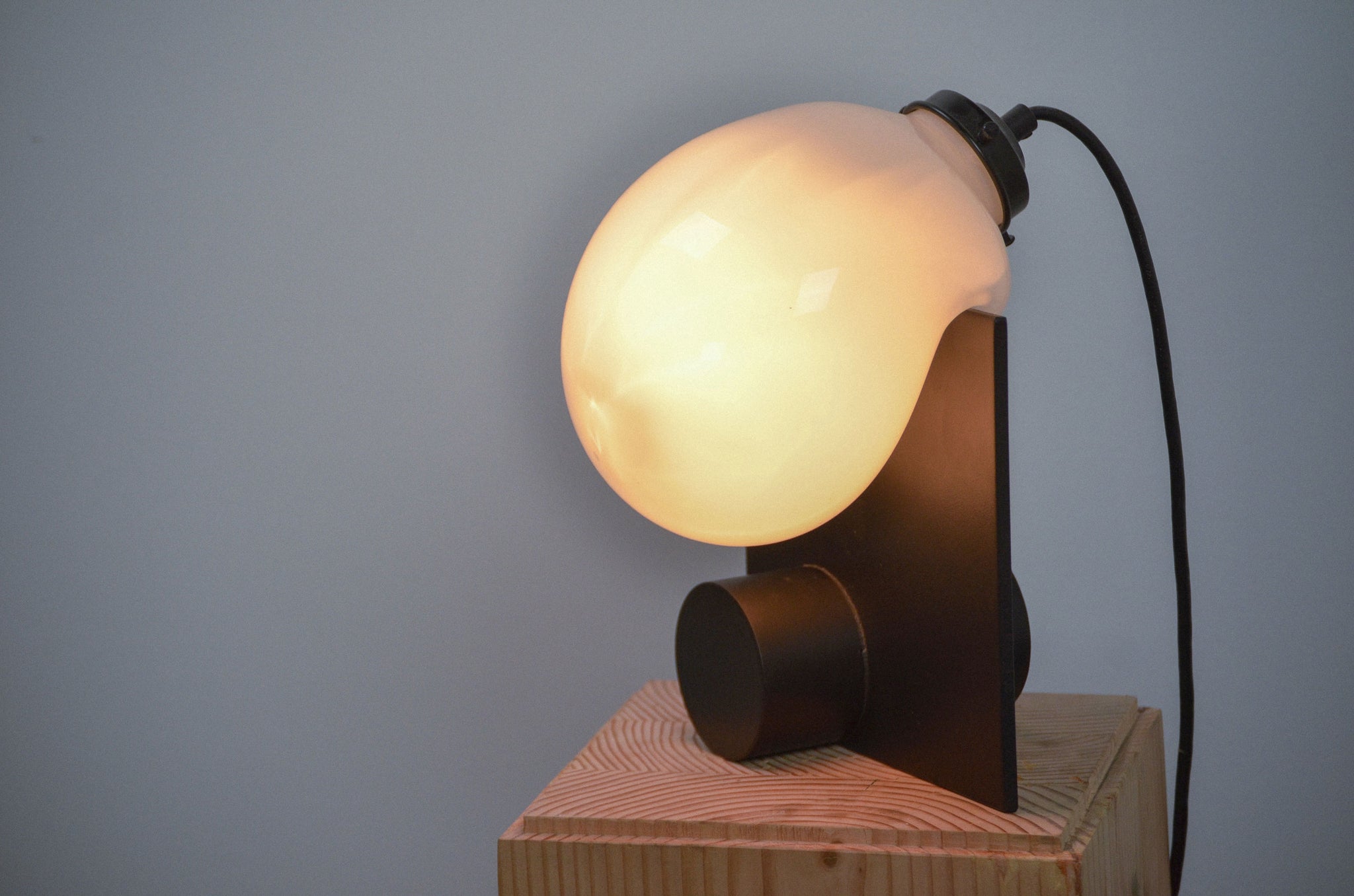 Close-up of the Bloop Table Lamp lit on a wood pedestal