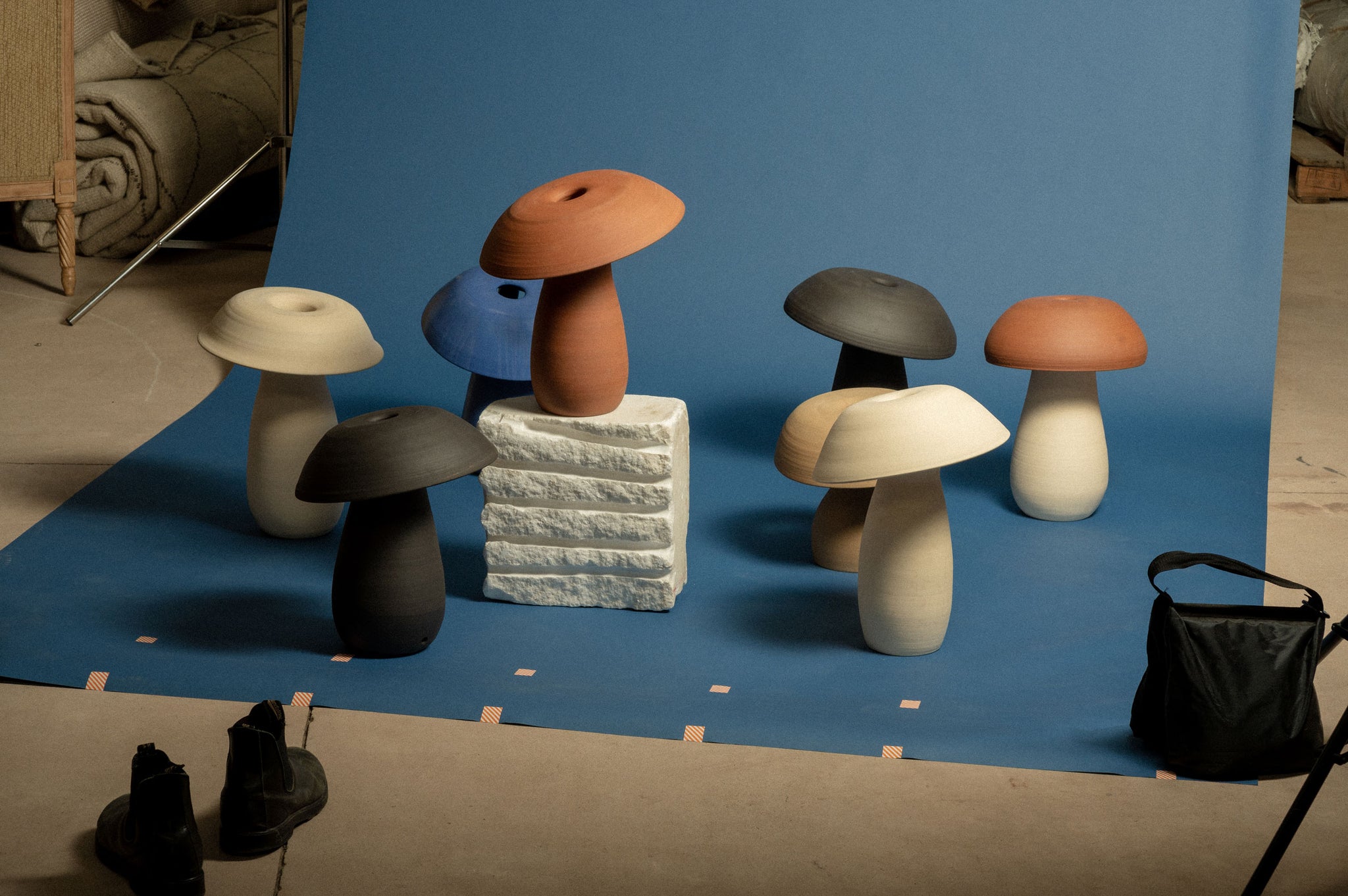 Behind the scenes of shooting the Terracotta, Blue, Black, White, and other variations of the Mushroom Lamp arranged on a blue backdrop