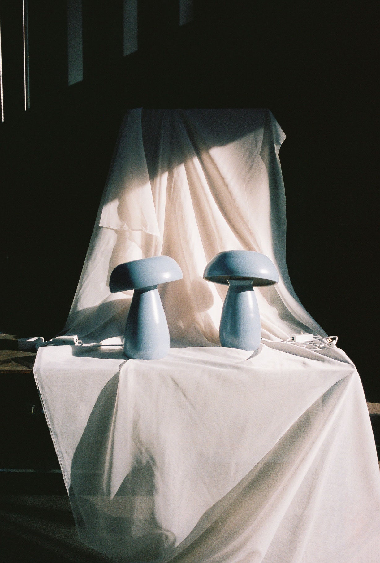 Two Stone Blue Mushroom Lamps shot resting on a sheer cloth