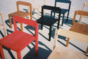 Red, Black, Blue, and an assortment of natural finish Anything Chairs arranged on concrete.